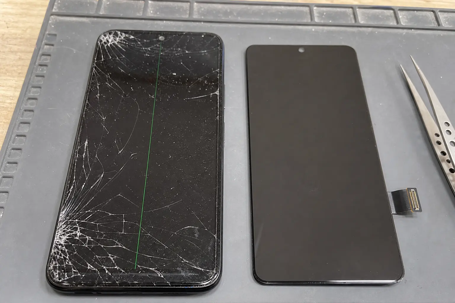 Damaged smartphone display beside a replacement screen assembly