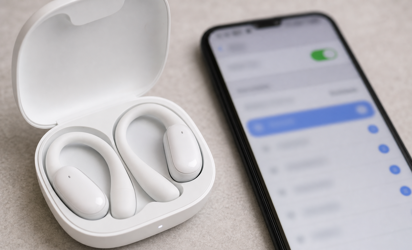 Open-fit white wireless earbuds in a charging case beside a smartphone