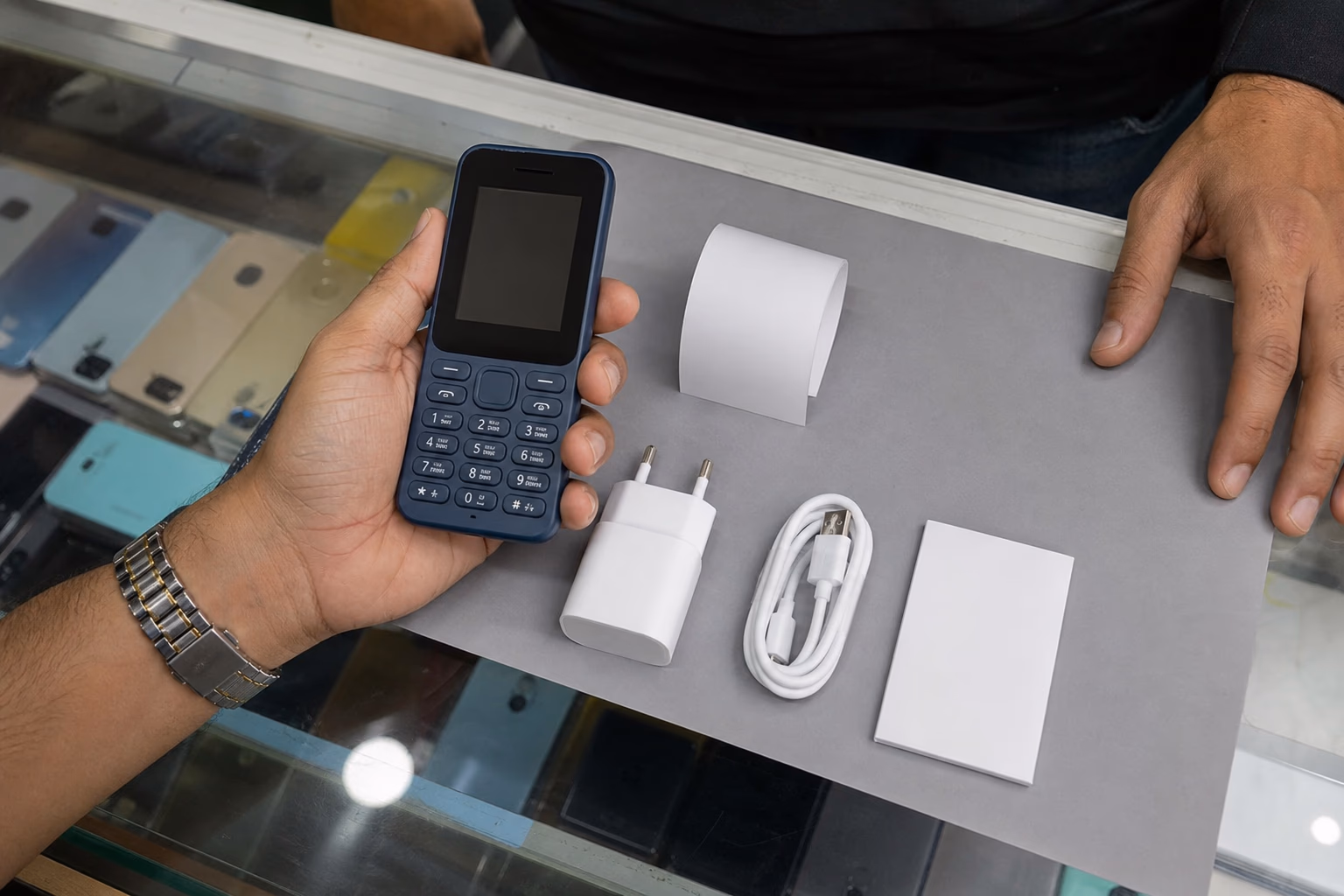 Buyer checking a feature phone with charger and retail pack items