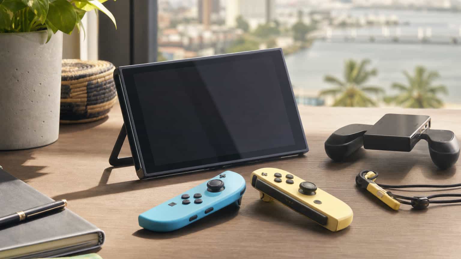 Blue and light yellow controller halves beside a handheld gaming console on a desk