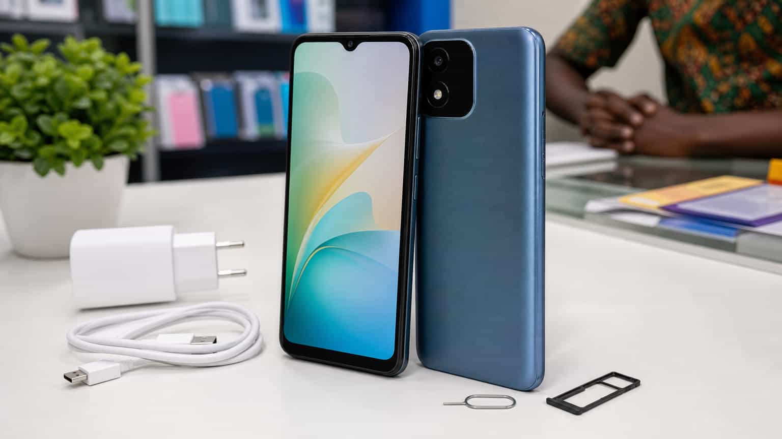 Budget Itel-style smartphone displayed with charger and SIM tray in a Nigerian retail setting