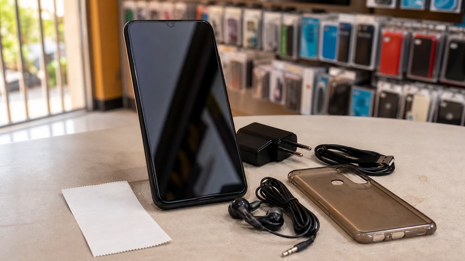 Itel A100C budget smartphone buying guide visual with phone, charger and everyday accessories