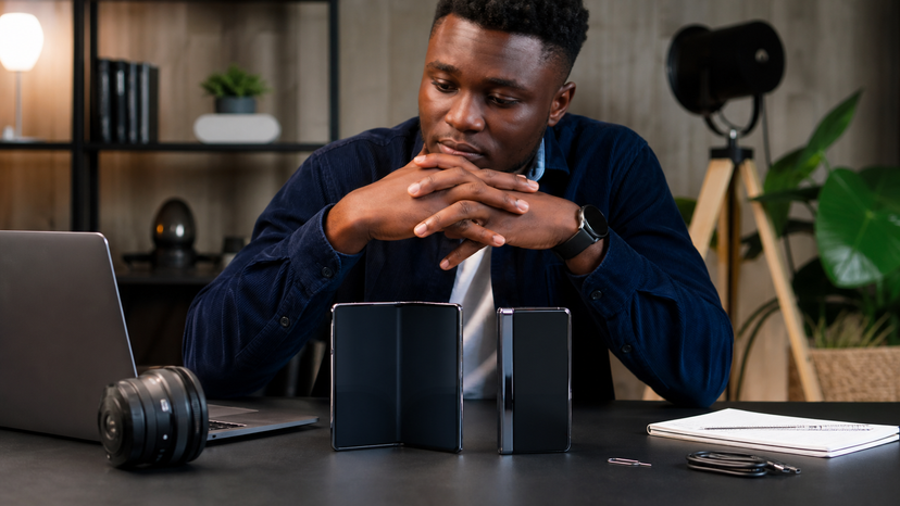 Realistic newsroom-style scene of foldable phones being reviewed on a desk with no logos or readable text