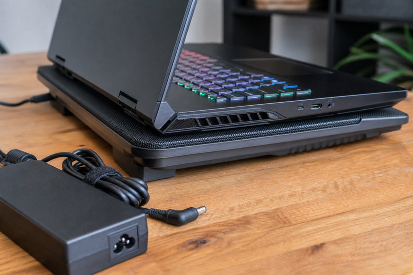 Gaming laptop cooling setup with power adapter and side vents visible