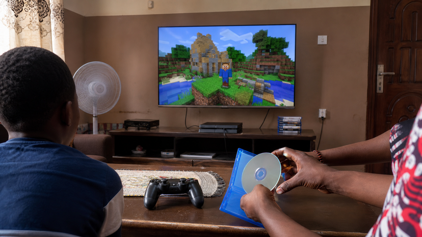 Family gaming setup with PS4 controller and colorful block-building game world on a television