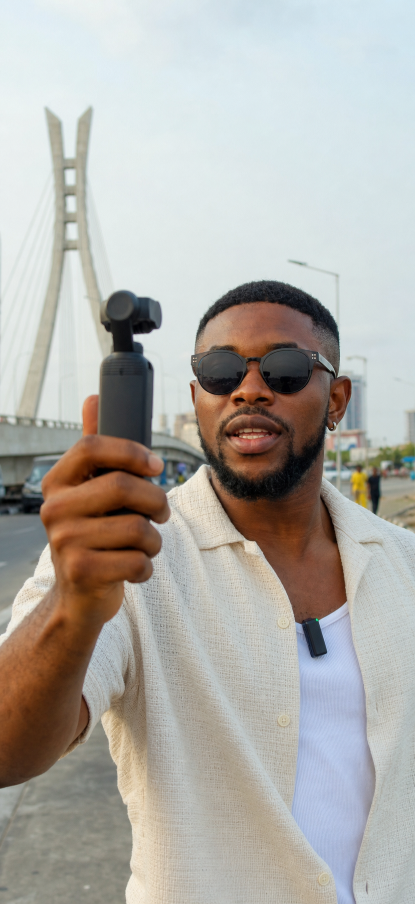 Nigerian creator filming handheld vertical video with a compact pocket gimbal camera and wireless microphone