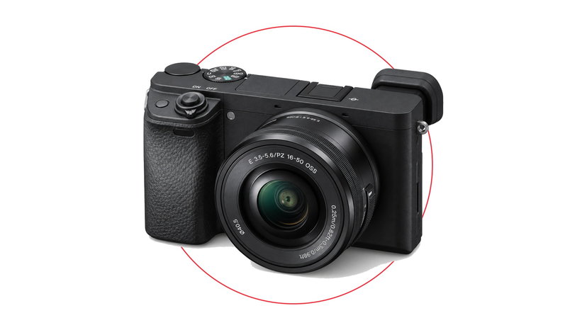 Compact mirrorless camera kit with collapsible zoom lens beside memory cards and a microphone